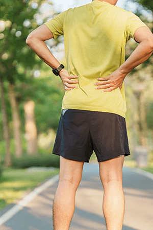 Man clutching his lower back, representing relief from back pain after Epidural Steroid Injections.