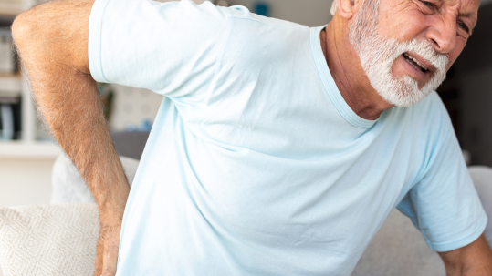 Older adult experiencing back pain, representing the challenges of chronic back pain and the importance of understanding its causes, treatments, and when to seek professional help.