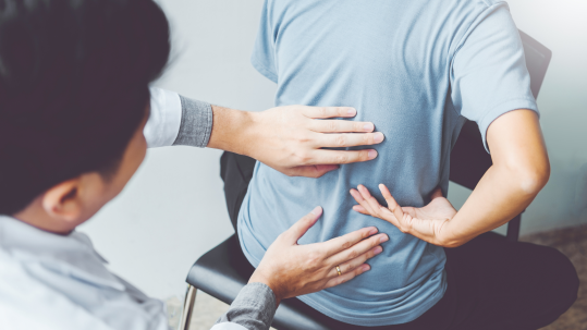 Doctor examining patient's back, illustrating the diagnosis and treatment of Sciatica, including pain management options.