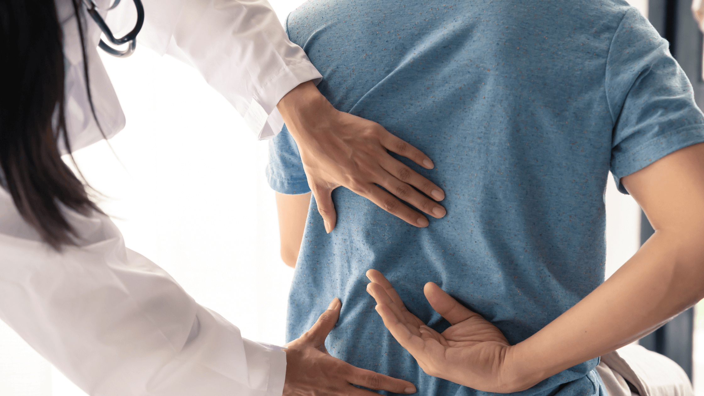A doctor gently examines a patient's back, focusing on the lumbar area, symbolizing a medical consultation for persistent back pain and the consideration of treatment options like steroid injections or regenerative medicine.