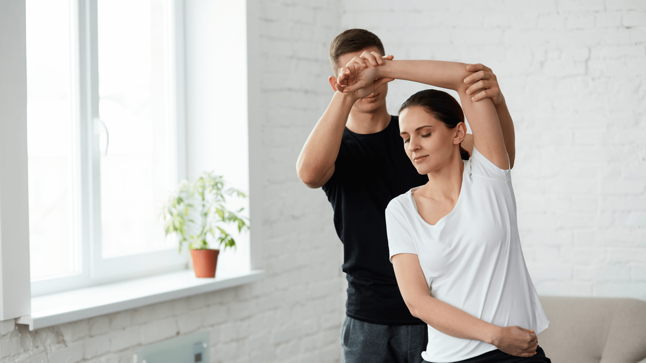 A physical therapist helps a woman with a gentle stretch, symbolizing the improved mobility and ability to participate in physical therapy that is made possible after receiving a nerve block injection for pain relief.