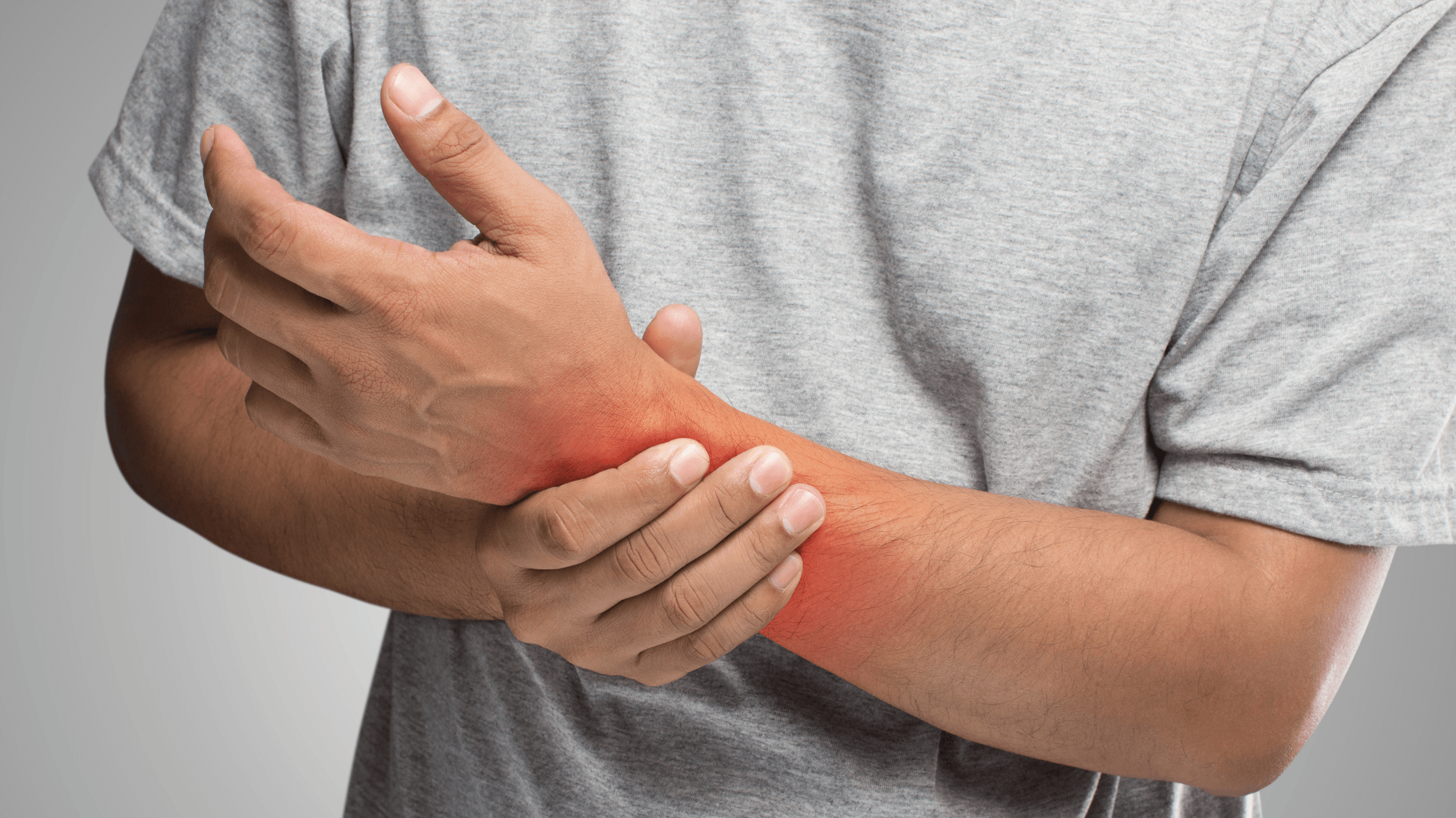 Close-up image of a person holding their wrist in pain with a red glow, symbolizing chronic joint or soft tissue pain that needs professional management and a personalized treatment plan in the new year.